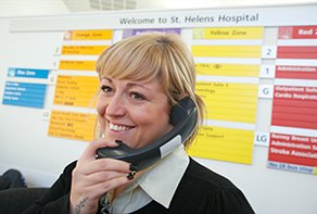 Photograph of a female receptionist talking on the telephone at St Helens Hospital