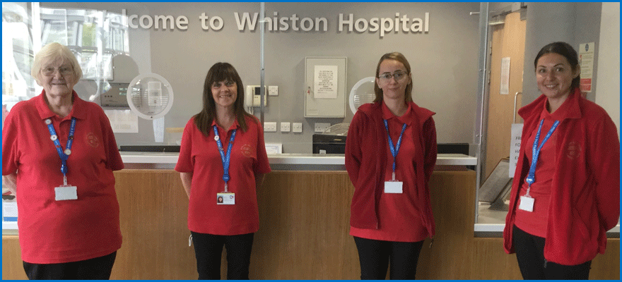 photograph of 4 volunteers stood in front of Whiston Hospital reception
